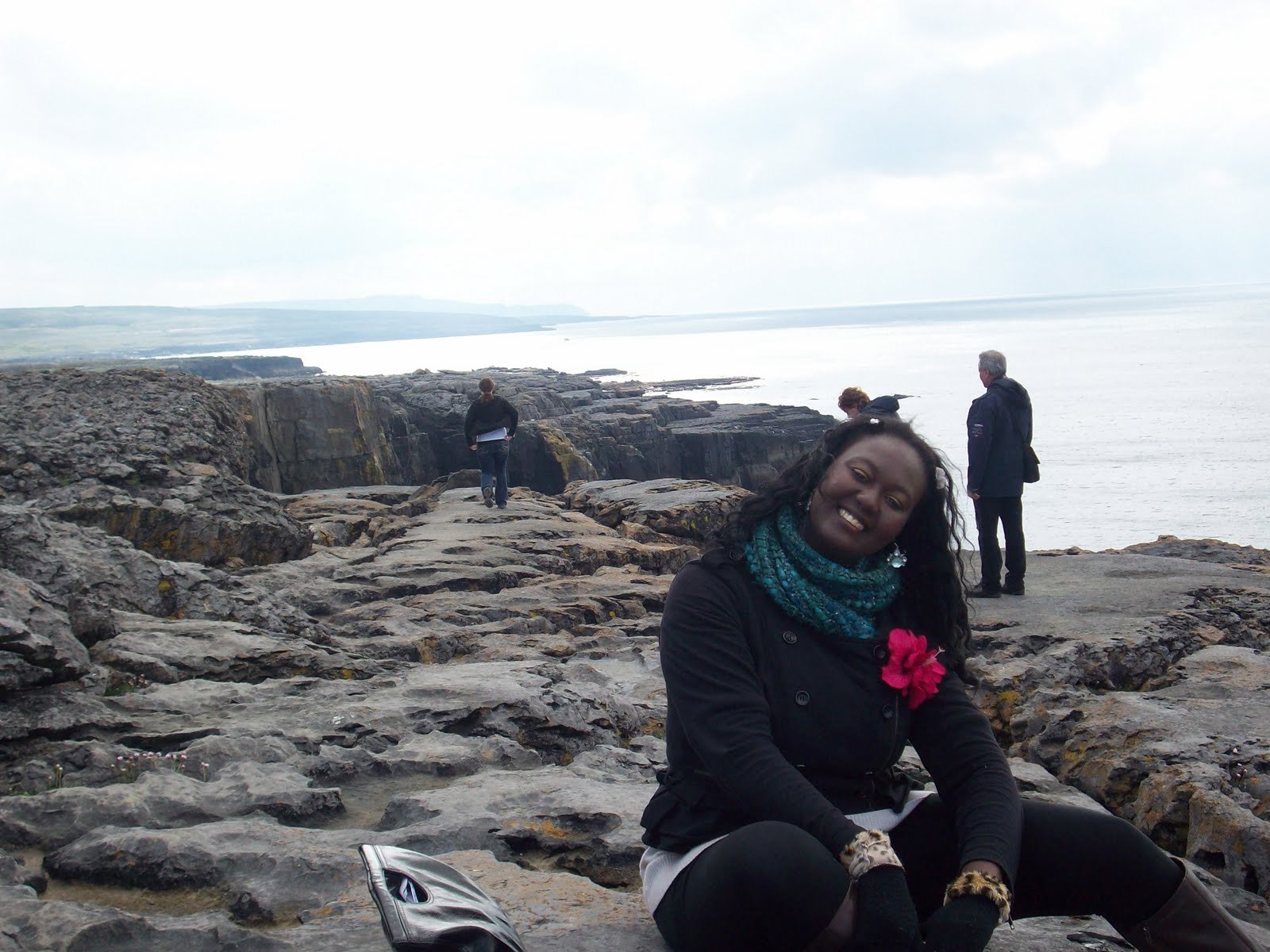 Traveler sitting among coastal rocks with the Atlantic cliffs and sea in the background