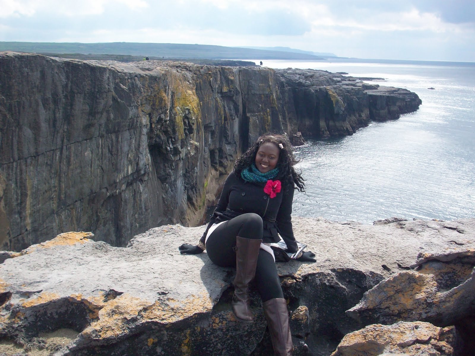 Traveler seated on rocks overlooking Ireland’s dramatic Atlantic sea cliffs